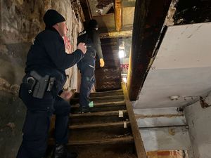 Zdjęcie przedstawia dwóch policjantów, którzy wchodzą po schodach w pustostanie.