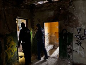 Zdjęcie przedstawia dwóch policjantów kontrolujących pomieszczenia w pustostanie.