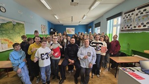 Zdjęcie przedstawia całą klasę podstawową, która pozuje do zdjęcia. Na zdjęciu widać również nauczyciela i policyjnego profilaktyka