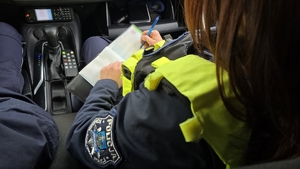 Zdjęcie przedstawia policjanta, który wypełnia formularz mandatu karnego
