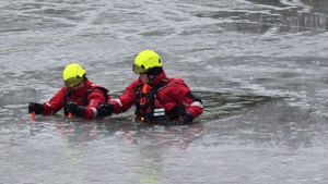 Zdjęcie przedstawia dwóch ratowników wodnych w przeręblu