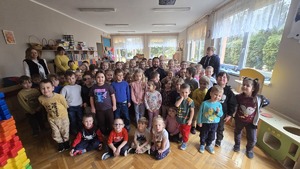 Na zdjęciu widnieje policjant wraz z przedszkolakami pozującymi do zdjęcia grupowego.