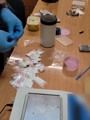 Na zdjęciu widoczne są dłonie policjanta, który sprawdza zawartość woreczków strunowych