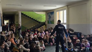 Zdjęcie przedstawia policjanta, który skierowany jest w tłum dzieci, którym przypomina zasady bezpieczeństwa