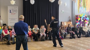 Na zdjęciu widać ratownika wodnego ochotniczego pogotowia ratunkowego wraz z policjantem, którzy omawiają zasady bezpieczeństwa dzieciom