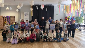 Zdjęcie przedstawia policjanta wraz z ratownikiem Wodnego Ochotniczego Pogotowia Ratunkowego, pozujących wraz z dziećmi z półkolonii do wspólnego zdjęcia.