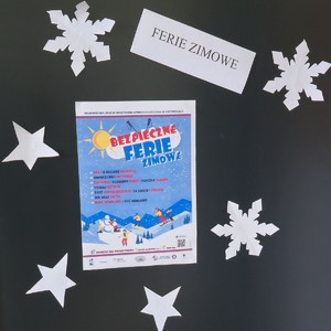 Na zdjęciu widnieje tablica z plakatem "Bezpieczne ferie 2026".