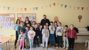 Na zdjęciu widnieją dzieci wraz z opiekunami półkolonii, którzy wraz z policjantem pozują do grupowego zdjęcia.