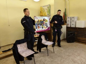 Zdjęcie przedstawia dwóch policjantów, którzy trzymają w ręku plakat