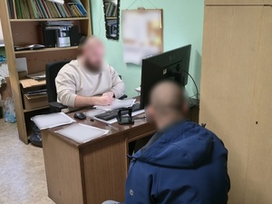 Zdjęcie przedstawia policjanta prowadzącego czynności procesowe z osobą zatrzymaną