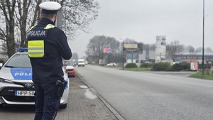 Zdjęcie przedstawia policjanta obserwującego ruch kołowy