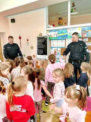Na zdjęciu widocznych jest dwóch policjantów i przedszkolacy