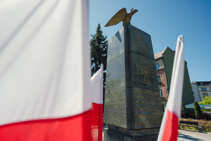Na zdjęciu widoczny jest pomnik i dwie flagi Polski