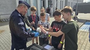 Zdjęcie przedstawia technika kryminalistycznego, który prezentuje sprzęt policyjny