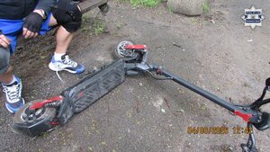 Na zdjęciu widoczny jest siedzący na ławce mężczyzna, a obok niego leżąca na ziemi hulajnoga elektryczna