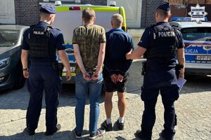 Na zdjęciu widocznych jest dwóch zatrzymanych mężczyzn oraz stojących przy nich dwóch policjantów
