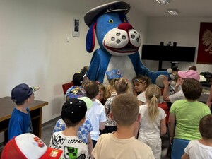 Zdjęcie przedstawia policyjną maskotkę Sznupka w otoczeniu dzieci