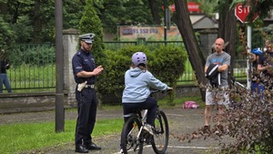 Zdjęcie przedstawia egzaminującego policjanta, który przekazuje wskazówki uczniowi