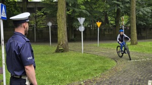 Na zdjęciu widać obserwującego policjanta przejazd ucznia szkoły