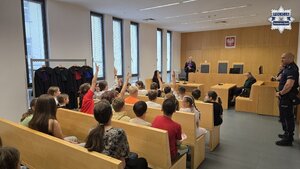 Na zdjęciu widoczna jest sala rozpraw, na której siedzą dzieci, a w jej tle widoczni są policjanci oraz przedstawiciele sądu