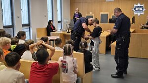 Na zdjęciu policjanci pokazowo zakładają kajdanki ochotnikowi