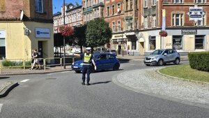 Na zdjęciu widoczny jest policjant ruchu drogowego na rondzie w trakcie ręcznego kierowania ruchem.