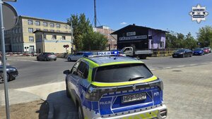 Zdjęcie przedstawia oznakowany radiowóz policji z włączonymi światłami pojazdu uprzywilejowanego