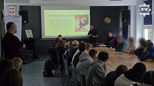 Na zdjęciu widać zaproszonego gościa oraz dzielnicowego, który przemawia do uczniów
